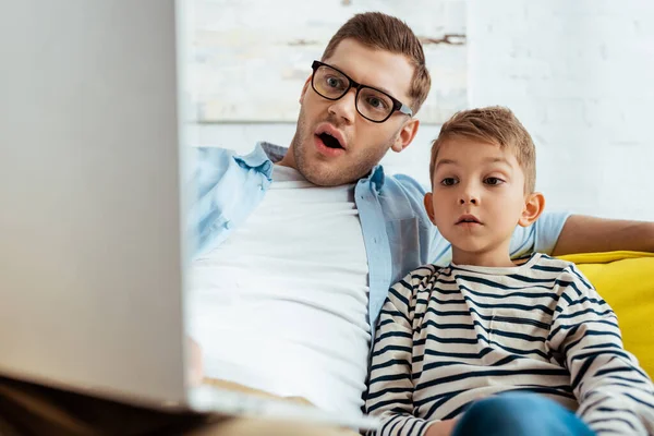 Selective focus of attentive son and excited father using laptop together — Stock Photo