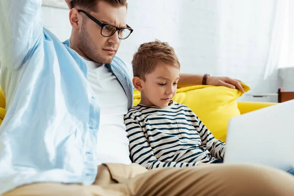 Homme réfléchi avec fils adorable en utilisant ordinateur portable ensemble — Photo de stock