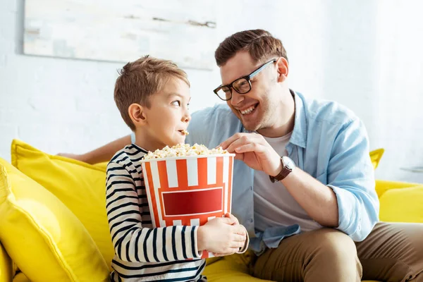 Glücklicher Vater und Sohn schauen sich beim Popcorn-Essen aus Eimer an — Stockfoto