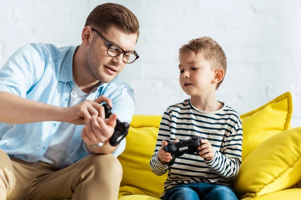 QUIIV, UCRÂNIA - JUNHO 9, 2020: jovem pai mostrando joystick ao filho atento — Fotografia de Stock