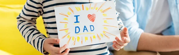 Cropped view of man near son showing fathers day greeting card with lettering and heart symbol, horizontal image — Stock Photo