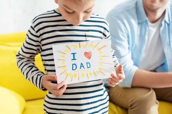 Cropped view of man near son showing fathers day greeting card with lettering and heart symbol — Stock Photo