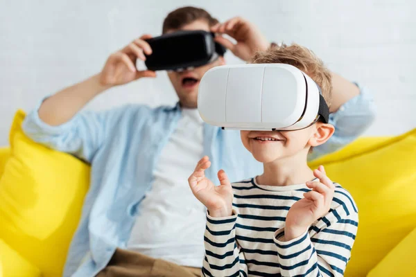 Selective focus of excited boy and surprised father using vr headsets — Stock Photo