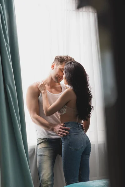 Selektiver Fokus einer sinnlichen Frau, die ihren Freund am Fenster küsst — Stockfoto