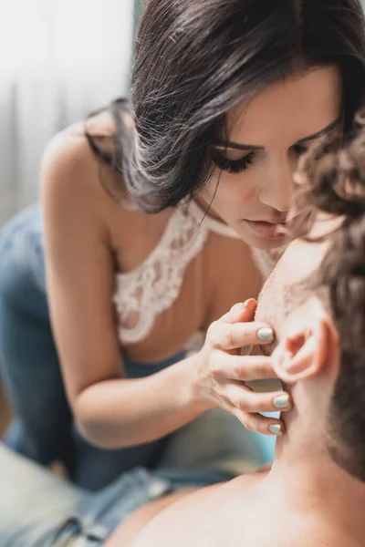 Focus selettivo di bella donna che bacia e tocca il viso del fidanzato senza maglietta a casa — Foto stock