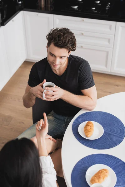 Vista aérea de la mujer coqueteando con novio guapo durante el desayuno en la cocina - foto de stock