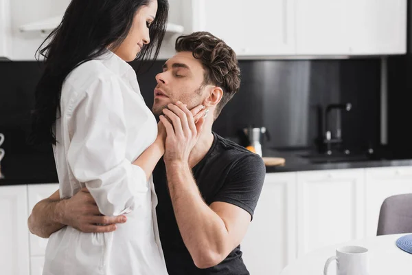 Bonito homem abraçando namorada atraente na cozinha — Fotografia de Stock