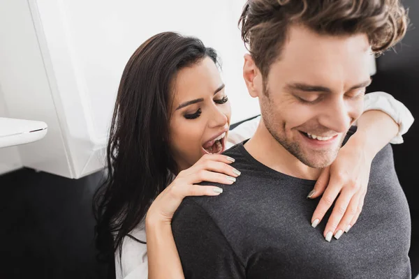 Foco seletivo de mulher bonita abraçando namorado sorridente na cozinha — Fotografia de Stock