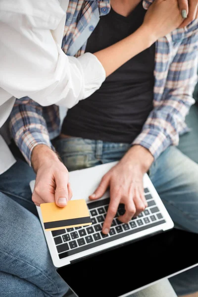 Vue du dessus de la femme embrassant petit ami en utilisant la carte de crédit et ordinateur portable à la maison — Photo de stock