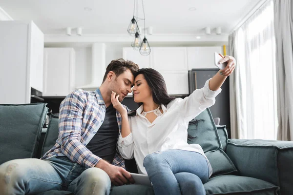 Selektiver Fokus der jungen Frau, die ihren Freund beim Selfie mit dem Smartphone zu Hause berührt — Stockfoto