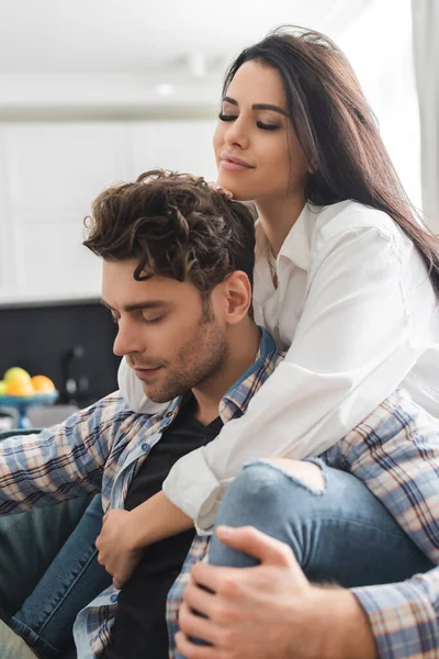 Selective focus of beautiful girl embracing handsome boyfriend with closed eyes at home — Stock Photo