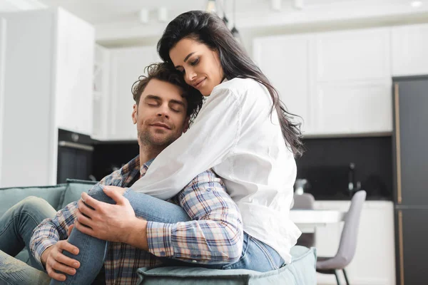Schöne Frau umarmt schönen Mann auf Couch im Wohnzimmer — Stockfoto