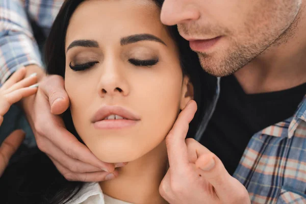 Selektiver Fokus des Mannes, der das Gesicht einer attraktiven Frau mit geschlossenen Augen berührt — Stockfoto