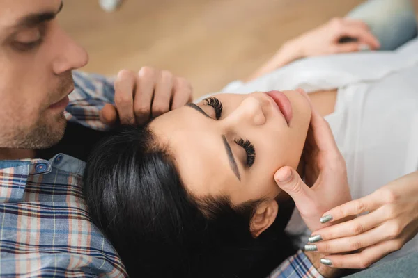 Selective focus of handsome man touching chin of beautiful girlfriend at home — Stock Photo