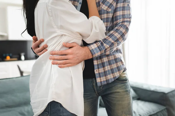 Recortado vista de hombre abrazando novia en casa - foto de stock