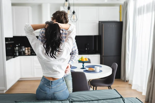 Homem tocando namorada segurando o cabelo no sofá em casa — Fotografia de Stock