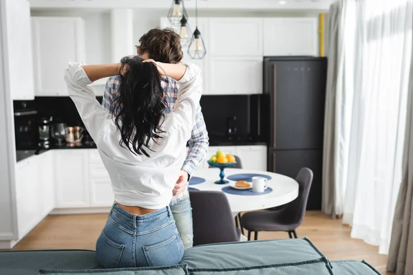 Hombre tocando novia sosteniendo pelo en sofá en casa - foto de stock