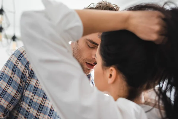 Selective focus of woman holding hair near boyfriend at home — Stock Photo