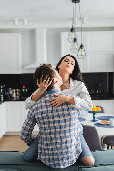 Mann küsst Hals von hübscher Freundin auf Couch zu Hause — Stockfoto