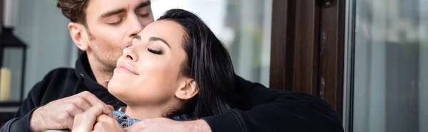 Panoramic crop of man kissing attractive girl on terrace — Stock Photo