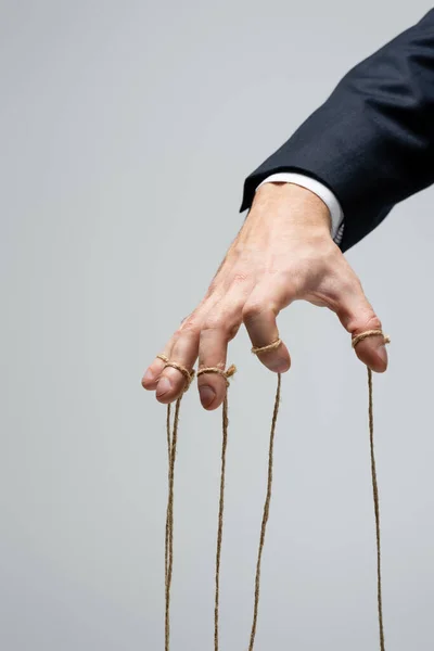 Cropped view of puppeteer with strings on fingers isolated on grey — Stock Photo