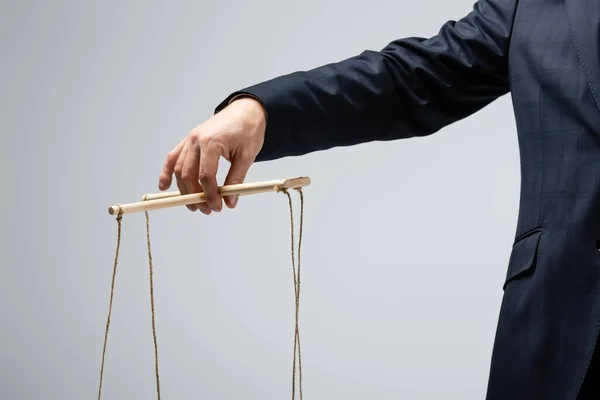 Cropped view of puppeteer holding marionette isolated on grey — Stock Photo