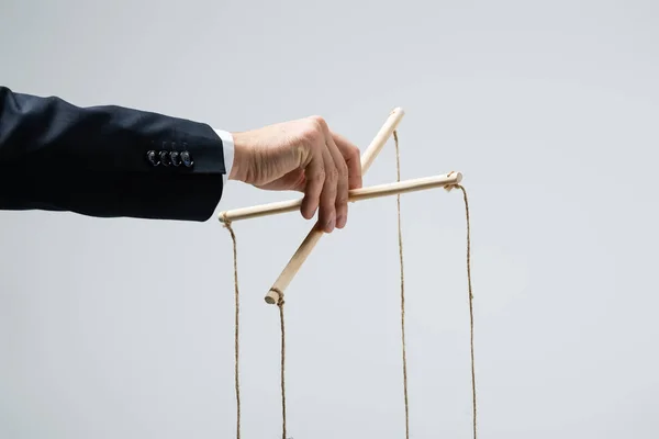 Cropped view of puppeteer in suit holding marionette isolated on grey — Stock Photo
