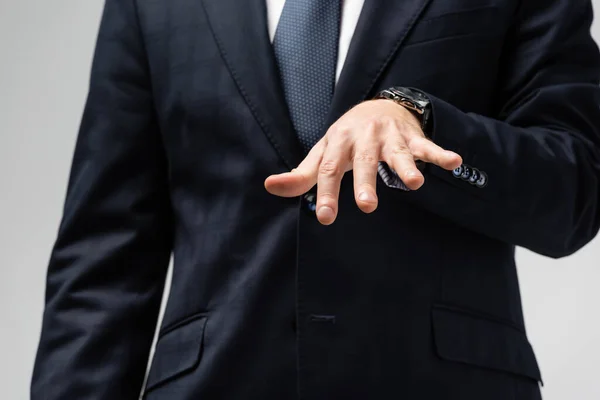 Abgeschnittene Ansicht eines Geschäftsmannes im Anzug, der mit einer Hand isoliert auf grau manipuliert — Stock Photo