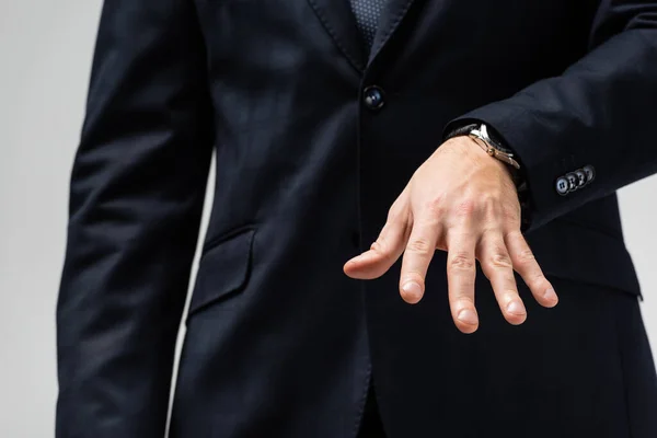 Vista recortada de hombre de negocios en traje manipulando con la mano aislada en gris - foto de stock