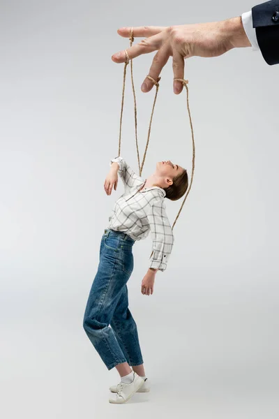 Cropped view of puppeteer holding marionette on strings isolated on grey — Stock Photo