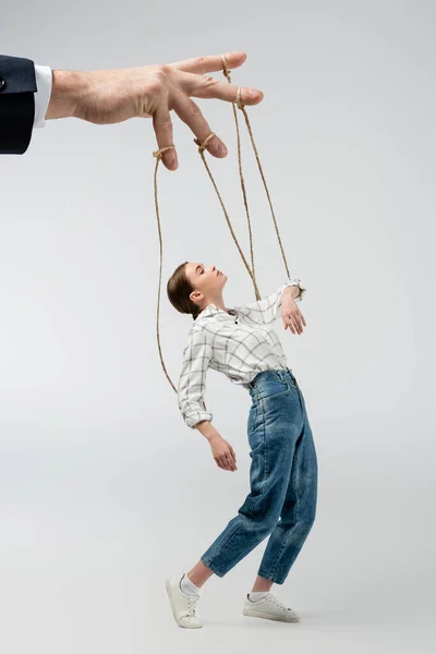 Vista recortada de titiritero sosteniendo marioneta en cuerdas aisladas en gris - foto de stock