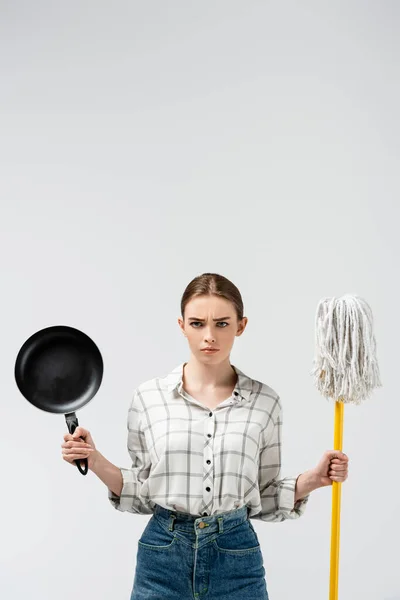 Attractive girl posing like puppet with mop and frying pan isolated on grey — Stock Photo