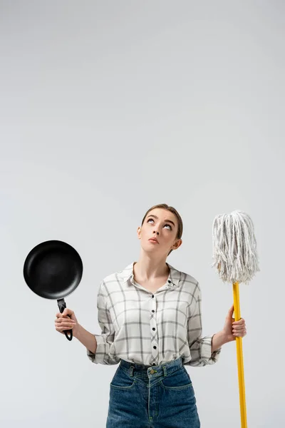 Attractive girl posing like puppet with mop and frying pan isolated on grey — Stock Photo