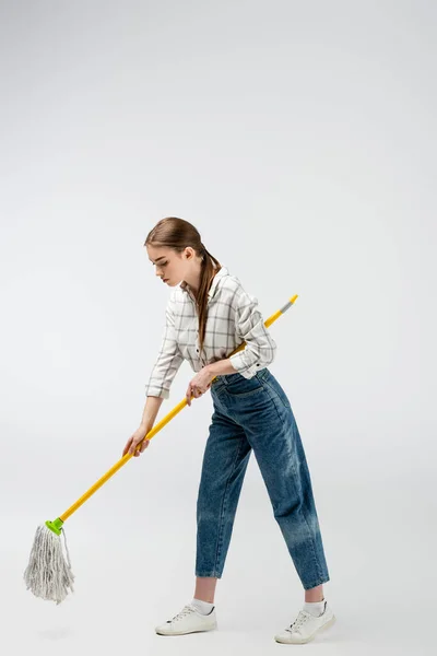 Attractive girl posing like puppet with mop and frying pan isolated on grey — Stock Photo