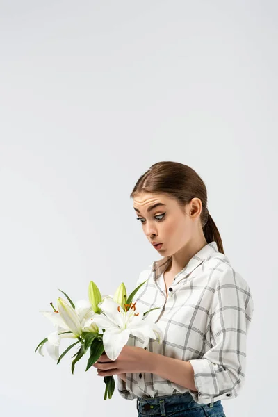 Chica atractiva sorprendida posando como marioneta con flores aisladas en gris - foto de stock