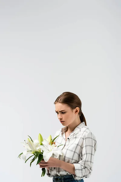 Confused attractive girl posing like puppet with flowers isolated on grey — Stock Photo
