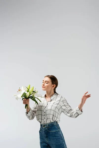Chica atractiva complacida posando como marioneta con flores aisladas en gris - foto de stock