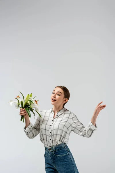 Happy attractive girl posing like puppet with flowers isolated on grey — Stock Photo