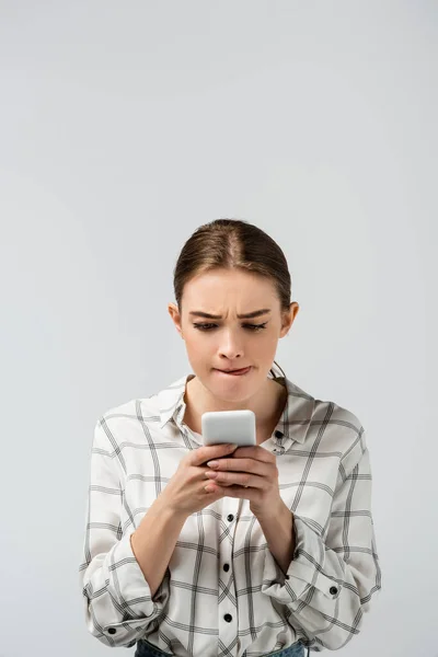 Chica atractiva concentrada usando teléfono inteligente aislado en gris - foto de stock