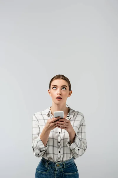 Surprised attractive girl using smartphone and looking up isolated on grey — Stock Photo