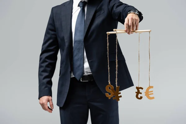 Cropped view of puppeteer in suit holding currency signs on strings isolated on grey — Stock Photo