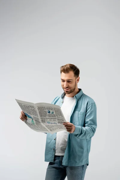 Sonriente joven leyendo periódico aislado en gris - foto de stock