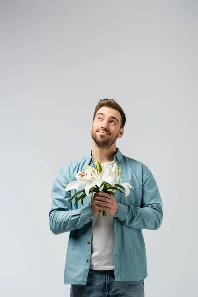 Joven soñador con ramo floral aislado en gris - foto de stock