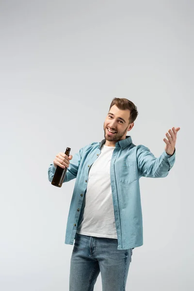 Jeune homme souriant avec bouteille de bière isolée sur gris — Photo de stock