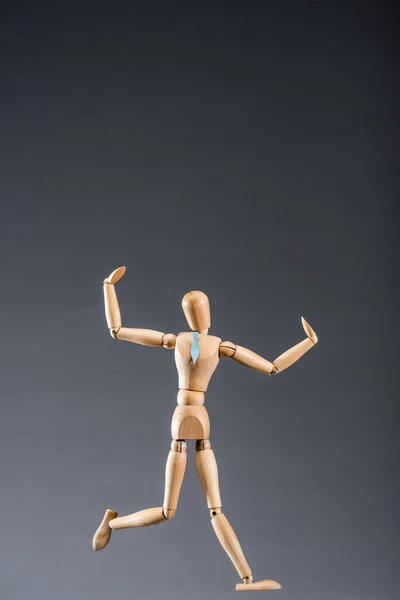 Wooden marionette in tie on black background — Stock Photo