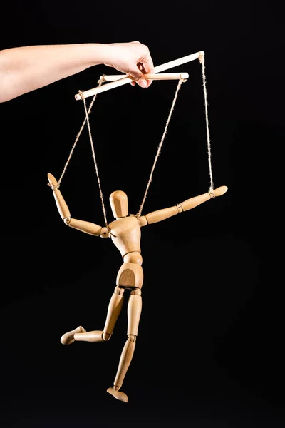 Cropped view of puppeteer holding wooden marionette isolated on black — Stock Photo