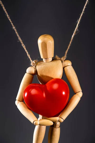 Vista de cerca de la marioneta de madera en cuerdas con corazón rojo aislado en negro - foto de stock