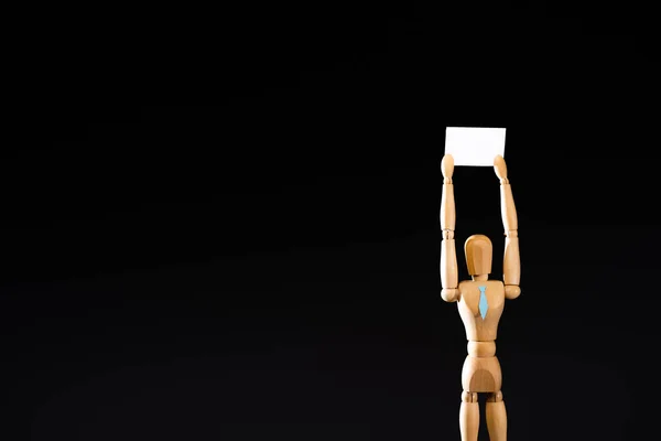 Wooden marionette in tie holding blank placard isolated on black — Stock Photo