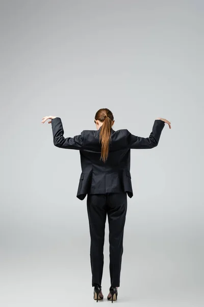 Vue arrière de marionnette femme d'affaires en costume posant isolé sur gris — Photo de stock