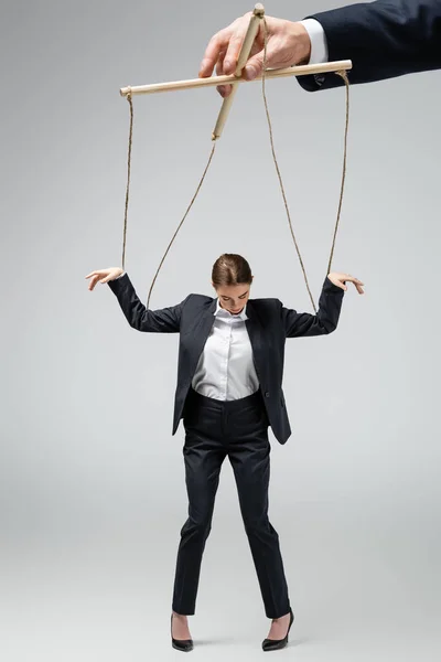 Vista ritagliata di burattinaio azienda donna d'affari marionetta su corde isolate su grigio — Foto stock